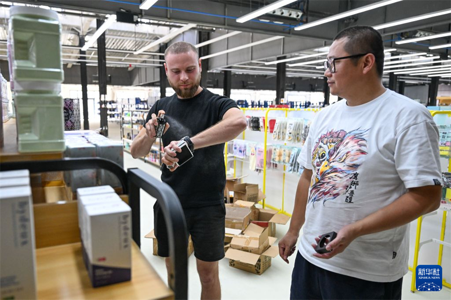 在新疆中哈霍尔果斯国际边境合作中心，来自哈萨克斯坦的主播瓦列里·博洛托夫（左）在跨境电商孵化中心选品（8月21日摄）。新华社记者 丁磊 摄